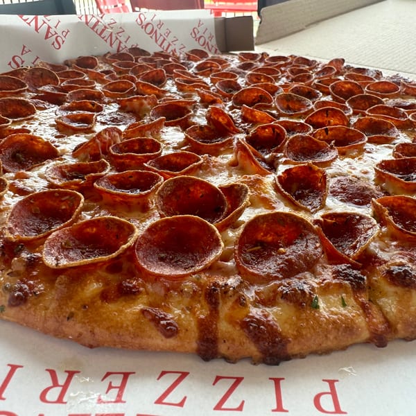 Close-up of a Santino's Pizzeria pepperoni pizza with crispy, curled pepperoni cups and melted cheese.