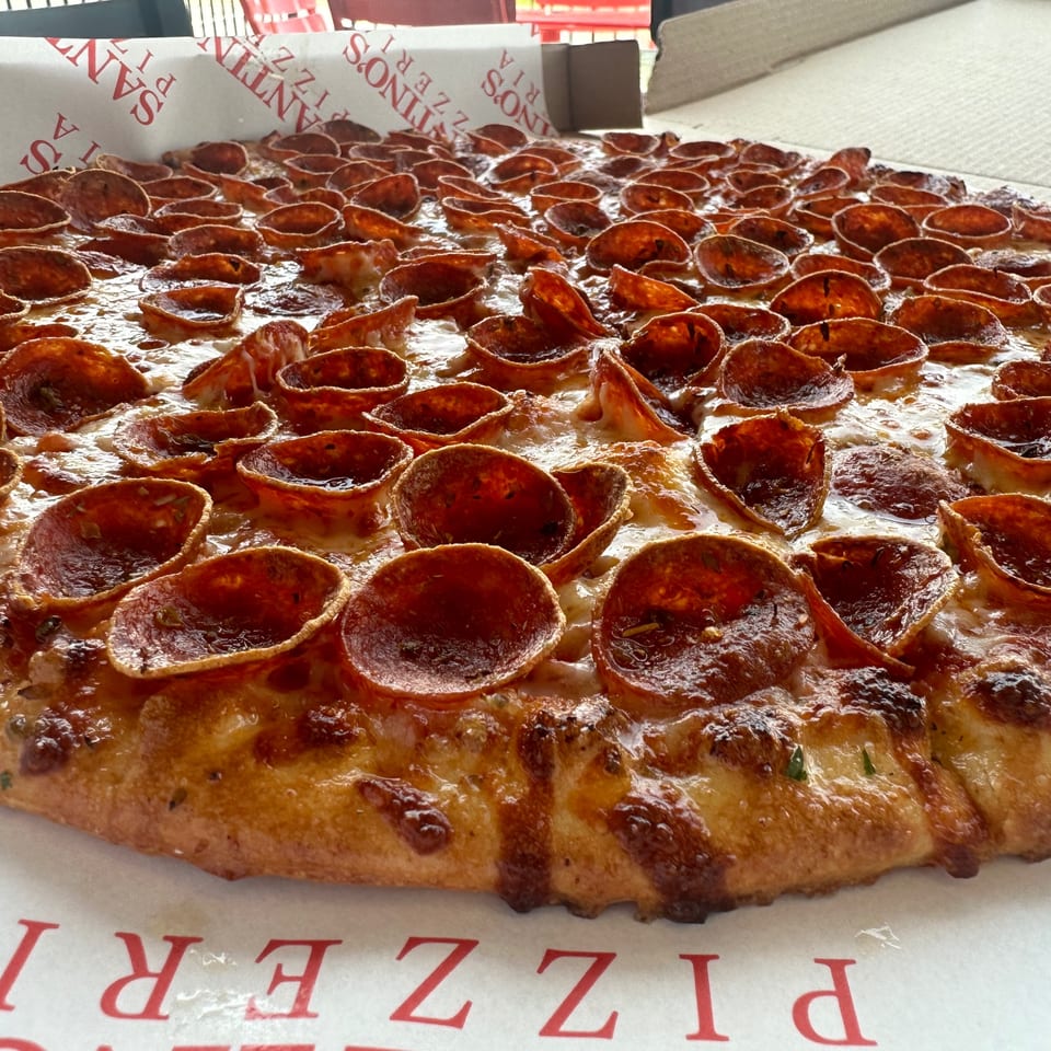 Close-up of a Santino's Pizzeria pepperoni pizza with crispy, curled pepperoni cups and melted cheese.