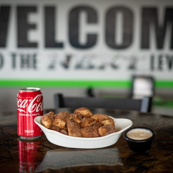 Cinnamon sugar dessert knots with dipping sauce and a Coca-Cola can on a dark table.