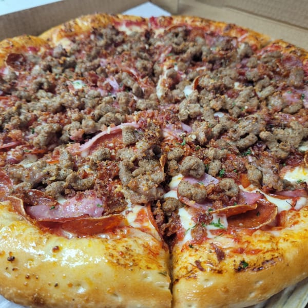 Close-up of a Santino's Pizzeria meat lover's pizza with sausage, pepperoni, and ham.