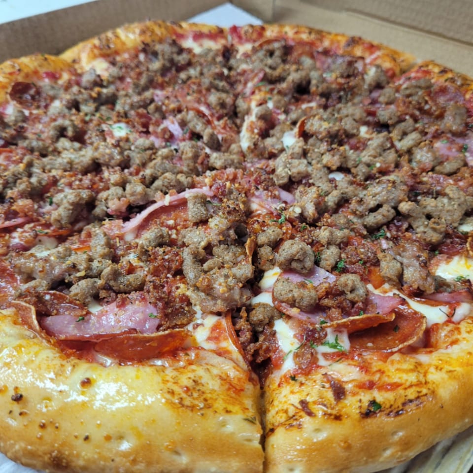 Close-up of a Santino's Pizzeria meat lover's pizza with sausage, pepperoni, and ham.