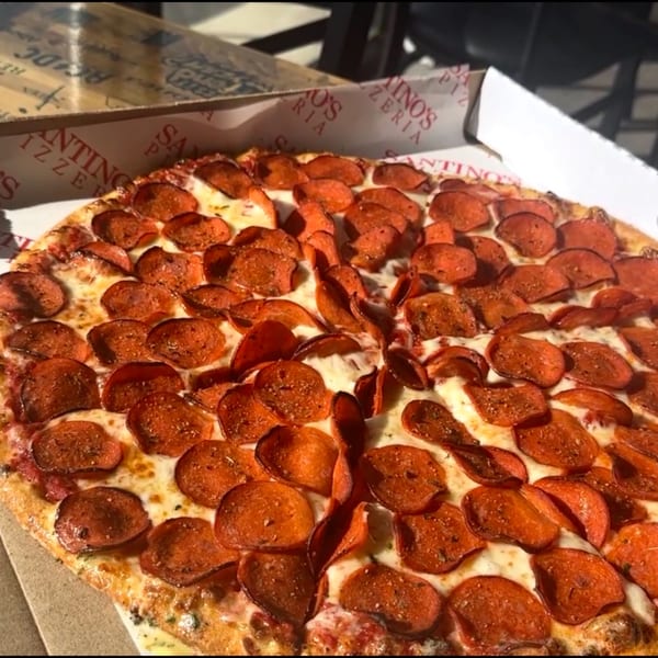 A close-up of a Santino's Pizzeria pepperoni pizza in a box, with melted cheese and crispy pepperoni.